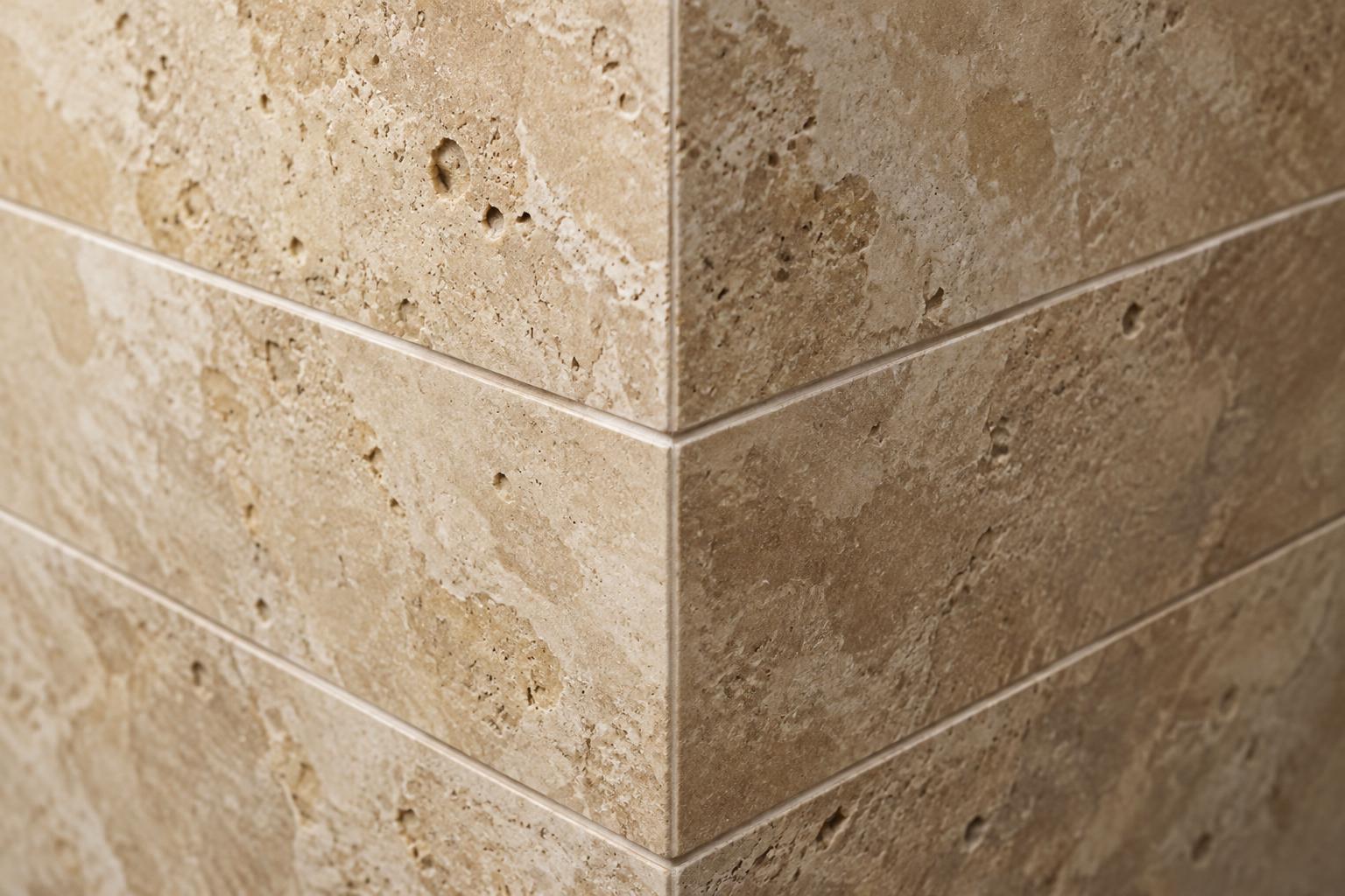Close-up of a precisely aligned travertine tile corner with a straight, consistent grout joint